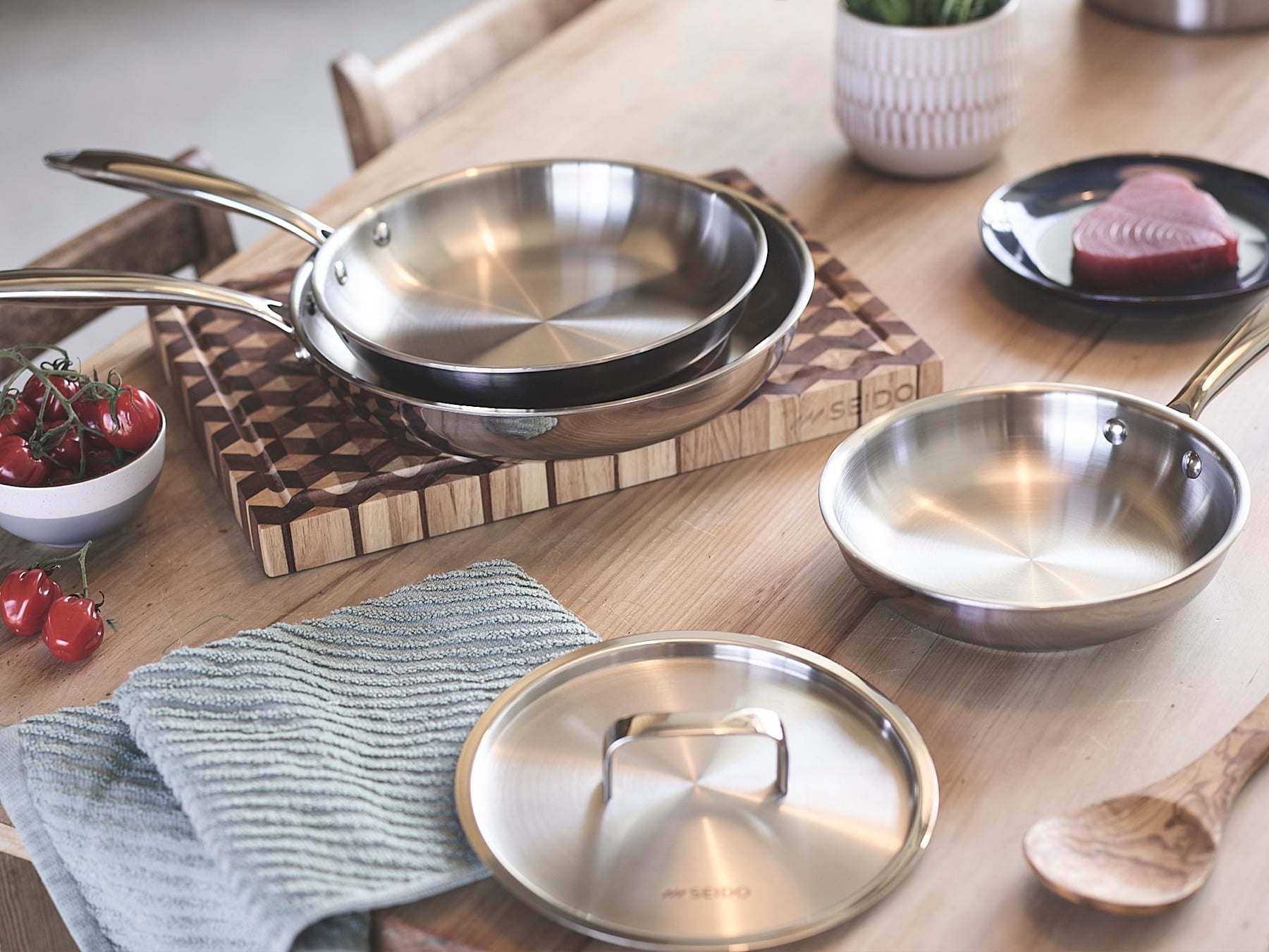 The Sear Series frying pan family with a lid on a wooden board