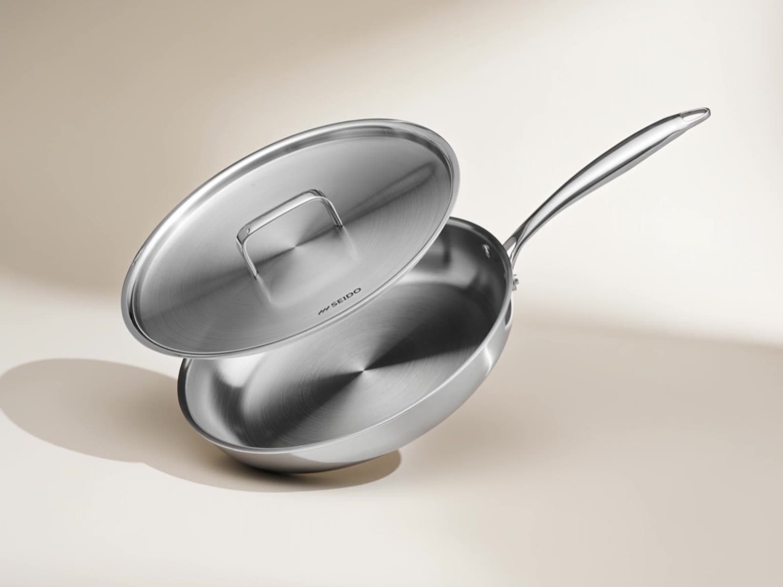 SEIDO stainless steel frying pan with lid on a cream background