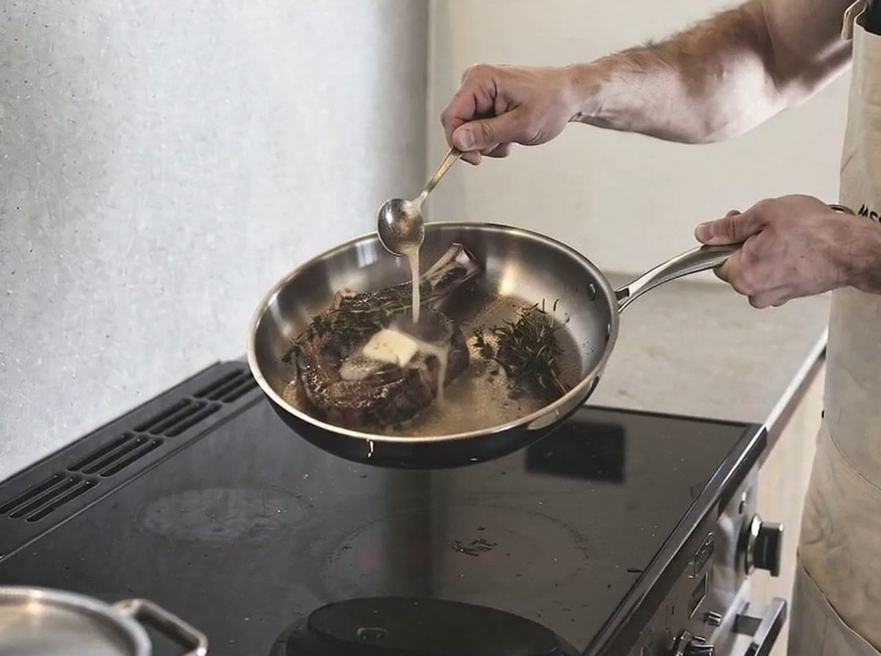 Steak searing in an uncoated stainless steel frying pan